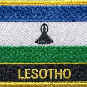 May include: A blue, white, green and black embroidered patch with the word "LESOTHO" in yellow lettering.