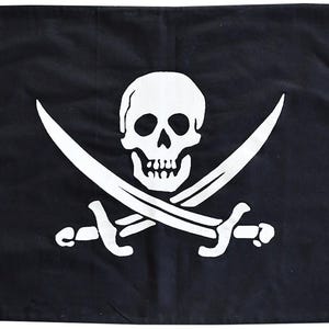 Könnte beinhalten: Eine rechteckige schwarze Flagge mit einem weißen Siebdruckmotiv, das einen menschlichen Schädel über zwei gekreuzten Schwertern zeigt. Die Flagge verfügt über vier Metallösen, eine in jeder Ecke, zur Befestigung.