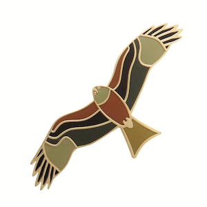May include: A gold-toned metal pin shaped like a stylized hawk in flight. The hawk has brown, black, and green enamel details.