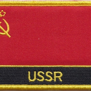 Puede incluir: Un parche rojo bordado con un borde dorado y un martillo y una hoz amarillos con una estrella. El parche tiene el texto "URSS" en letras amarillas sobre un fondo negro.