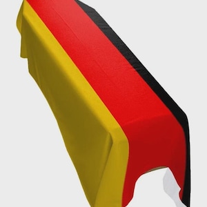 Peut inclure: Un chemin de table rectangulaire aux couleurs du drapeau allemand. Le tissu est jaune, rouge et noir. Le tissu est drapé sur une table, mettant en valeur le motif et les couleurs du drapeau.