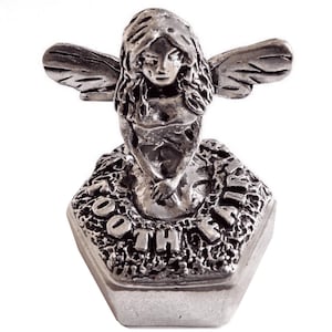 Puede incluir: Figura de hada plateada con alas detalladas y cabello suelto. El hada está arrodillada sobre una base hexagonal con la inscripción "GOTH FAIRY". La figura es de metal y tiene una superficie detallada y texturizada.