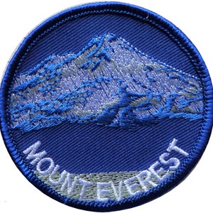 May include: A blue and white embroidered patch with the words "Mount Everest" in white lettering.