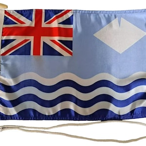 Op de afbeelding: Een blauwe vlag met een witte ruit en golven, en een rood-wit-blauwe Union Jack in de linkerbovenhoek. De vlag heeft een wit touw eraan bevestigd.