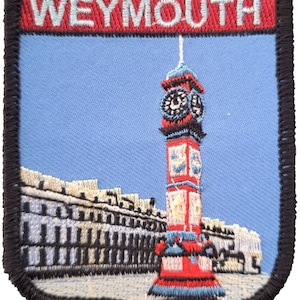 May include: Embroidered patch featuring a red clock tower with a blue sky background. The text "WEYMOUTH" is embroidered in white on a red banner at the top of the patch.
