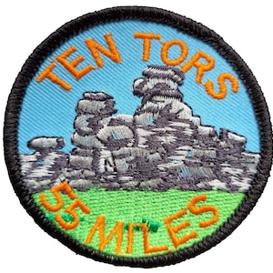 May include: A round, embroidered patch with a blue background and orange text. The text reads "Ten Tors 35 Miles". The patch features a gray, embroidered image of a rock formation.