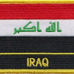 Op de afbeelding: Een gele geborduurde patch met de vlag van Irak. De vlag heeft drie horizontale strepen: rood, wit en zwart. De witte streep bevat groene Arabische tekst. Onderaan de patch staat het woord "IRAQ" in groene tekst.