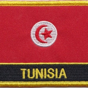 Könnte beinhalten: Ein roter gestickter Aufnäher mit einem weißen Kreis, der einen roten Halbmond und einen roten fünfzackigen Stern enthält. Der Aufnäher hat einen schwarzen Rand und einen gelben Rand um die Außenseite. Der Text "TUNISIEN" ist in gelben Buchstaben auf schwarzem Hintergrund am unteren Rand des Aufnähers geschrieben.
