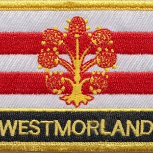 May include: A white and red striped patch with a gold embroidered tree in the center. The bottom of the patch is black with the word "WESTMORLAND" in gold lettering.