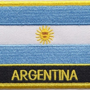 Könnte beinhalten: Ein blauer und weißer gestickter Aufnäher mit einer gelben Sonne und dem Wort "ARGENTINA" in gelben Buchstaben auf schwarzem Hintergrund.