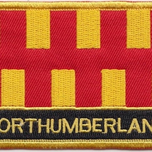 May include: A red and yellow embroidered patch with the word "NORTHUMBERLAND" in yellow lettering on a black background.