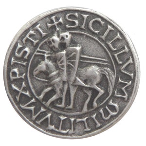 May include: A silver-toned metal coin featuring a raised image of a knight on horseback. The coin is inscribed with "SIGILLVM REGNI SICILIAE" around the edge.