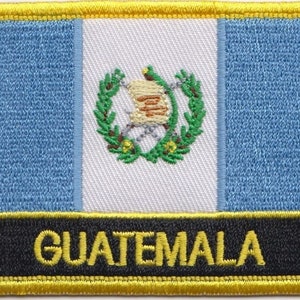 Pode incluir: Um remendo bordado azul, branco e verde com a palavra "GUATEMALA" em letras amarelas sobre um fundo preto. O remendo tem uma borda amarela.