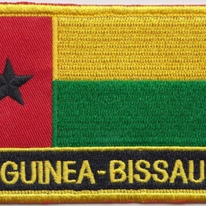May include: Embroidered patch featuring the flag of Guinea-Bissau. The flag has a red field with a black star in the top left corner, a yellow field to the right of the red field, and a green field below the yellow field. The patch has a black border with the text "GUINEA-BISSAU" in yellow.