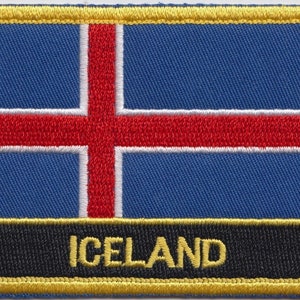 Puede incluir: Un parche bordado azul y blanco con una cruz roja y la palabra "ICELAND" en letras amarillas sobre un fondo negro.