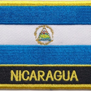 May include: A blue, white, and blue embroidered patch with a gold emblem in the center and the word "NICARAGUA" in gold lettering on a black background.
