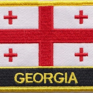 May include: A white patch with a red cross in each corner and a larger red cross in the center. The patch has a black border with the word "GEORGIA" in yellow letters.