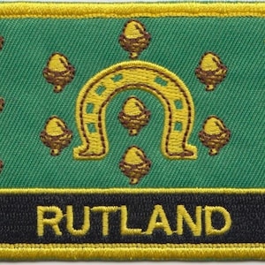 May include: An embroidered patch in green and yellow featuring a horseshoe and acorns. The text "RUTLAND" is embroidered in yellow on a black background.