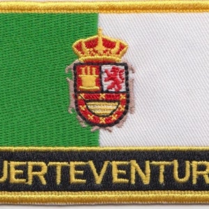 Pode incluir: Um remendo bordado verde e branco com um brasão de armas e o texto "FUERTEVENTURA" em letras amarelas.