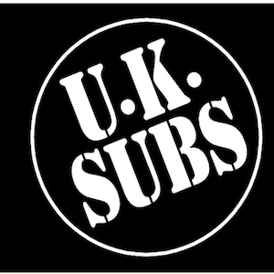 Pode incluir: Uma bandeira preta e branca com um círculo branco contendo o texto "U.K. SUBS" em uma fonte branca, em negrito e sem serifa.
