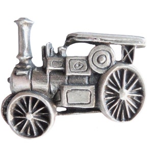 Puede incluir: Un pin de estaño plateado de una máquina de vapor vintage con una chimenea grande y dos ruedas grandes.