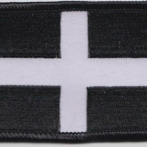 May include: A black and white patch with a white cross in the centre. The patch has a black border.