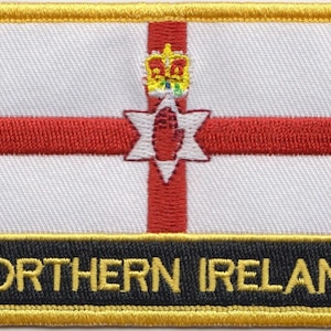 May include: A white patch with a red cross and a red hand inside a six-pointed star. The cross is topped with a gold crown. The patch has a black border with the text "NORTHERN IRELAND" in gold letters.