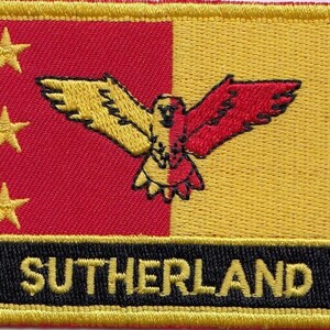 May include: An embroidered patch in yellow and red with a black outline. The patch features a stylised bird with three gold stars on the left side and the word "SUTHERLAND" in black lettering at the bottom.