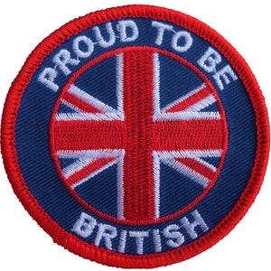 May include: A circular patch with a blue background and a red border. The central design is the Union Jack flag in red and white. The words "PROUD TO BE BRITISH" are embroidered in white around the flag.
