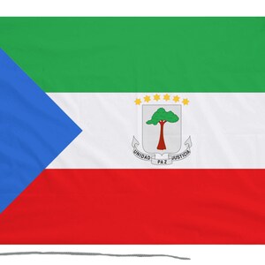 Op de afbeelding: De vlag van Equatoriaal-Guinea, met een horizontale driekleur in groen, wit en rood met een blauwe driehoek aan de mastzijde. In het midden van de vlag bevindt zich het nationale wapen, dat een boom met een rode stam en groene bladeren toont, omringd door zes gele sterren.
