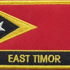 Puede incluir: Parche bordado con la bandera de Timor Oriental. El diseño incluye un fondo rojo, un triángulo negro con una estrella blanca y un borde amarillo. El texto "EAST TIMOR" se muestra en amarillo.