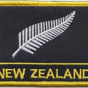 May include: Black fabric patch with a white embroidered silver fern and the text "NEW ZEALAND" in yellow embroidery.