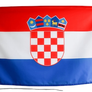 May include: A Croatian flag with a red, white, and blue horizontal stripe design. The flag features a coat of arms with a checkered shield in the center.