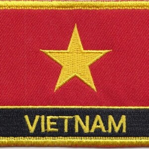 Op de afbeelding: Een geborduurde patch met een rode achtergrond, een gele ster en het woord "VIETNAM" in gele letters op een zwarte achtergrond.