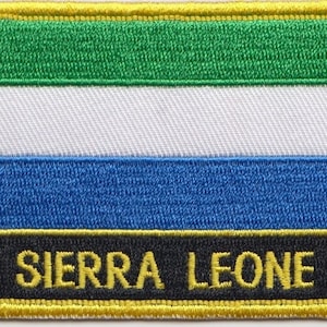 Könnte beinhalten: Ein gestickter Aufnäher mit gelbem Rand, der die Flagge von Sierra Leone in Grün, Weiß, Blau und Schwarz zeigt. Der Aufnäher enthält auch den Text "SIERRA LEONE".