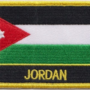 Könnte beinhalten: Ein gestickter Aufnäher mit der Flagge Jordaniens. Die Flagge ist rot, weiß, grün und schwarz mit einem siebenzackigen Stern im roten Dreieck. Der Aufnäher hat einen gelben Rand und das Wort "JORDAN" in gelben Buchstaben auf schwarzem Hintergrund.