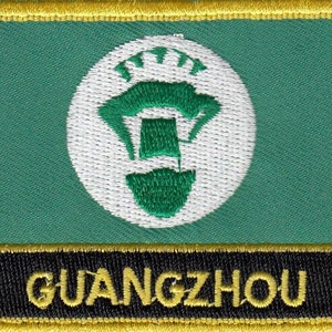 Op de afbeelding: Een geborduurde patch in groen en wit met een gestileerd beeld van een toren en het woord "GUANGZHOU" in gele letters op een zwarte achtergrond.