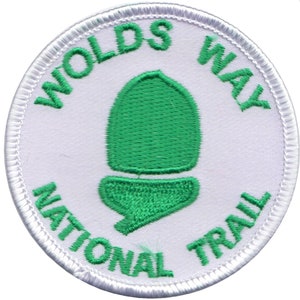 Puede incluir: Parche blanco bordado con un diseño de bellota verde y el texto "Wolds Way National Trail".