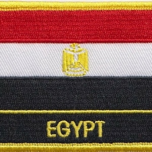 May include: An embroidered patch with the flag of Egypt. The flag is red, white, and black with a gold eagle in the center. The words "EGYPT" are embroidered in gold at the bottom of the patch.