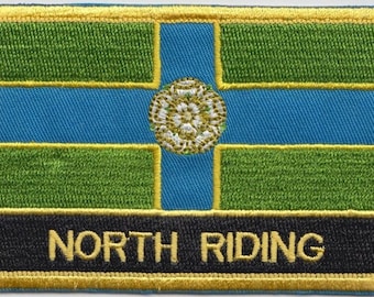 May include: A green, blue, and white embroidered patch with a gold border. The patch features a white rose with a gold center and the text "NORTH RIDING" in gold letters on a black background.