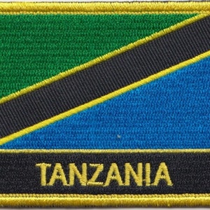 Pode incluir: Um remendo bordado com a bandeira da Tanzânia, com a palavra "TANZANIA" em letras amarelas sobre um fundo preto.
