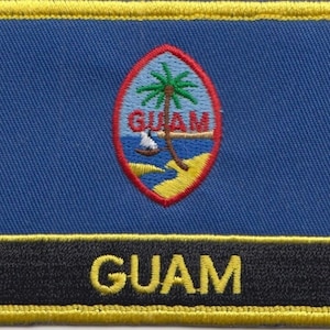 May include: A yellow embroidered patch with a blue background and a red oval containing a palm tree and the word "GUAM". The bottom of the patch has a black background with the word "GUAM" in yellow.