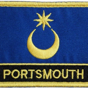 Pode incluir: Um remendo bordado azul e dourado com um design de lua crescente e estrela. O texto "PORTSMOUTH" é bordado em dourado sobre um fundo preto.