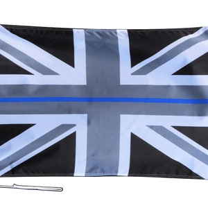 Puede incluir: Una bandera Union Jack en blanco y negro con una fina línea azul en el centro. La bandera está hecha de tela y ondea en un asta de bandera.