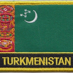 Op de afbeelding: Een groene geborduurde patch met een rood en gouden ontwerp in de linkerhoek en een witte halve maan en vijf sterren in de rechterhoek. De patch heeft een zwarte rand met het woord "TURKMENISTAN" in gele letters.