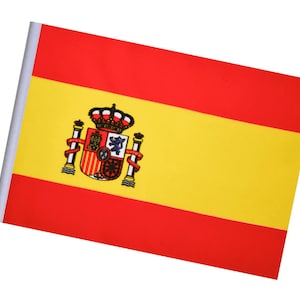 May include: A small Spanish flag with a red and yellow design. The flag features a coat of arms with a crown, a shield, and other emblems. The flag is mounted on a white pole.