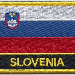 May include: A yellow-bordered patch with the Slovenian flag. The flag has three horizontal stripes: white, blue, and red. The white stripe features the Slovenian coat of arms. The bottom stripe is black with the word "SLOVENIA" in yellow lettering.
