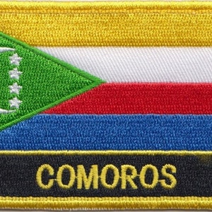 Op de afbeelding: Een geborduurde patch met de vlag van Comoren, met het woord "COMOROS" in gele letters op een zwarte achtergrond.