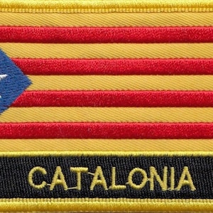 Könnte beinhalten: Ein gestickter Aufnäher in Gelb und Rot mit einem blauen Dreieck, das einen weißen Stern enthält. Der Aufnäher hat einen schwarzen Rand mit dem Wort "CATALONIA" in gelben Buchstaben.