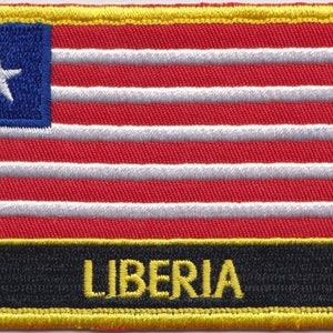 Może przedstawiać: Naszywka haftowana z flagą Liberii. Naszywka jest czerwona, biała i niebieska z białą gwiazdą w niebieskim kantonie. Naszywka ma czarne tło z napisem "LIBERIA" żółtymi literami.